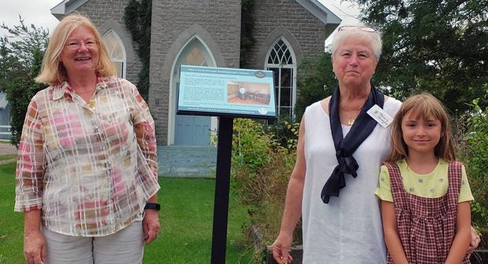 <p>A GOOD SIGN Janet Comeau, Beverly Sprague and a young Ameliasburgh Heritage Village volunteer with new signage.  (Chris Fanning/Gazette Staff)</p>
