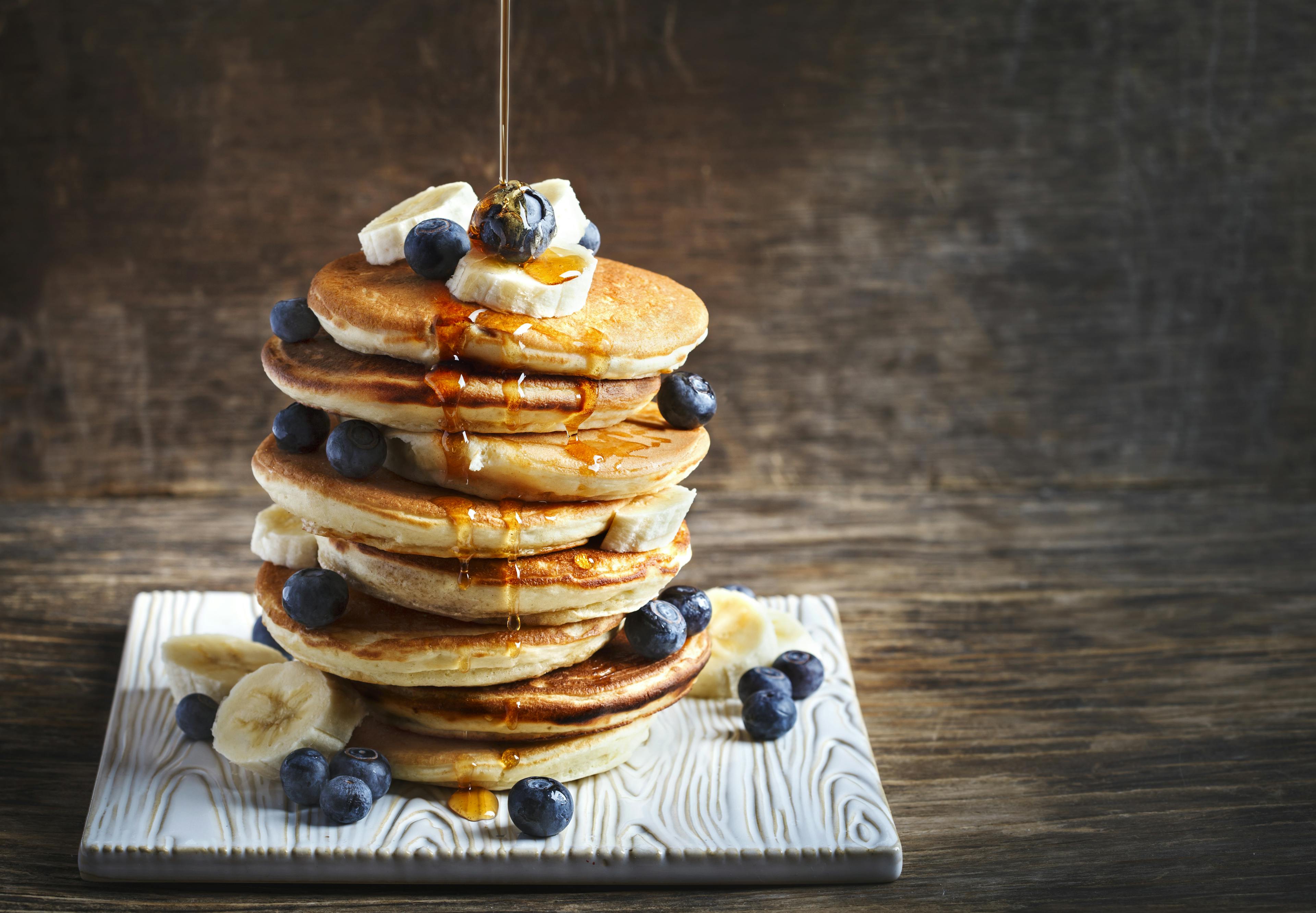 <p>Pancakes with banana, blueberry and maple syrup for a breakfast, wooden background, copy space</p>
